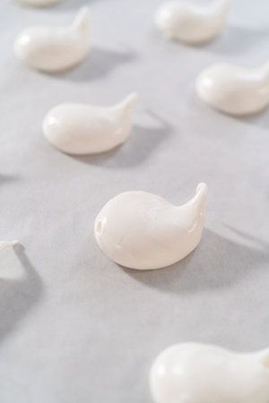 Piping meringue with piping bags into the baking sheet lined with parchment paper to bake Easter meringue cookies.の写真素材