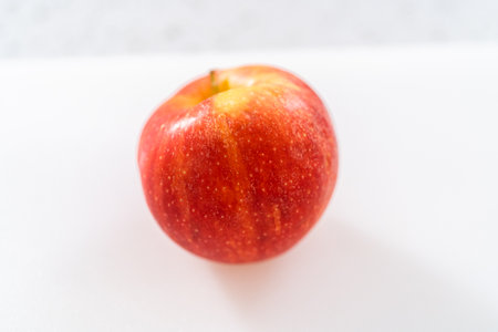 Slicing red apples into thin slices on a white cutting board.の写真素材