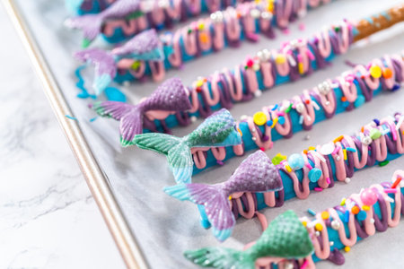 Mermaid chocolate pretzel rods drizzled with pink and purple chocolate and covered with sprinkles.の写真素材
