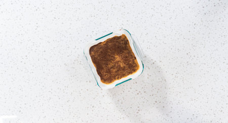 Flat lay. Pouring fudge mixture into the baking pan lined with parchment paper to prepare chocolate...