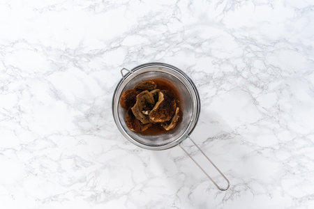 Flat lay. Soaking dehydrated wild mushrooms in a glass mixing bowl with hot water.の写真素材