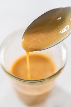 Spooning eggnog caramel sauce from the glass jar.の写真素材
