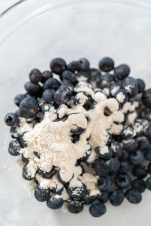 Coating fresh blueberries with all-purpose flour for baking.の写真素材