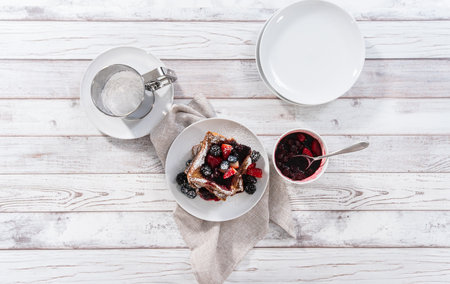 Stack of freshly made french toast garnished with mix berry compote and powder sugar.の写真素材