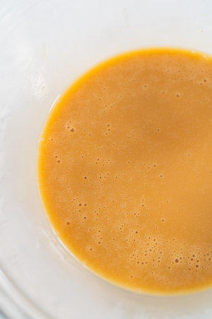 Mixing ingredients with a hand mixer in a small mixing bowl to make the eggnog caramel sauce.の写真素材