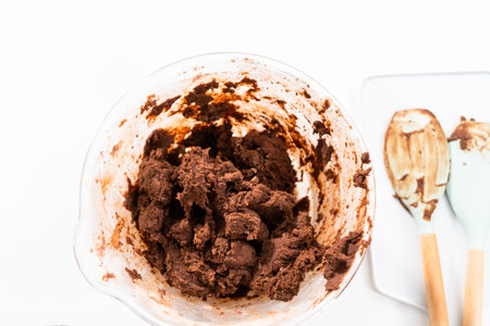 Mixing ingredients in a glass mixing bowl to bake chocolate cookies.の写真素材