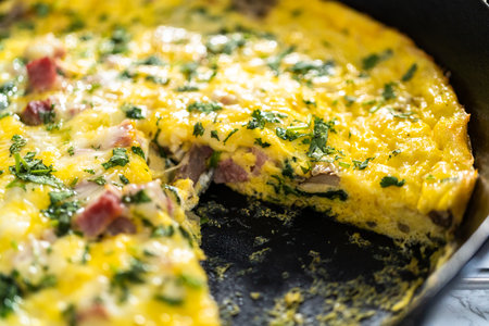 Freshly baked spinach and ham frittata in cast iron skillet.の写真素材