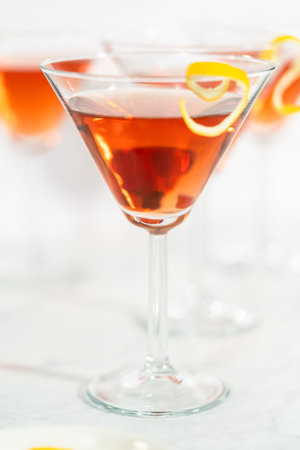 Cosmopolitan cocktail in a martini glass and decorated with a lemon swirl.