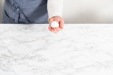 Peeling hard-boiled eggs at the marble kitchen counter.の写真素材