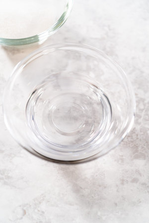 Measured ingredients in glass mixing bowls to prepare simple syrup.