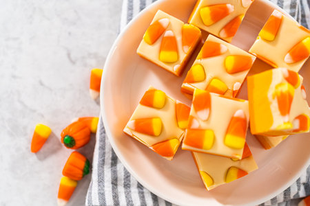 Homemade candy corn fudge square pieces on a white plate.の写真素材