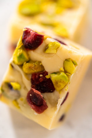 Homemade cranberry pistachio fudge square pieces on a kitchen counter.の写真素材