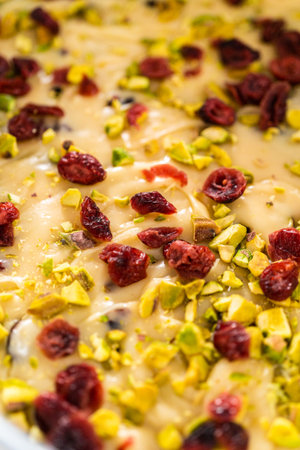 Removing cranberry pistachio fudge from a square cheesecake pan lined with parchment.の写真素材