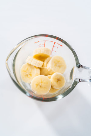 Slicing riped banana in a glass measuring cup.の写真素材