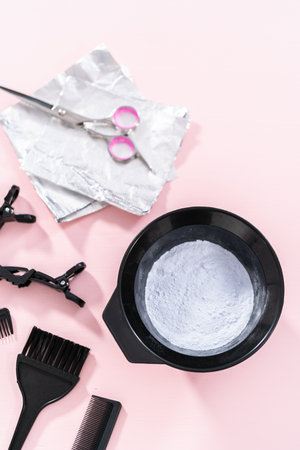 Hair color dye powder in a black plastic mixing bowl on a pink background.の写真素材