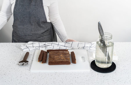 Cutting chocolate peanut butter fudge into small pieces on a white cutting board.