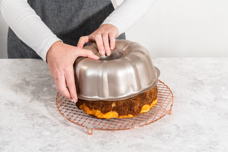 Removing freshly baked carrot bundt cake from the bundt cake pan to round the cooling rack.