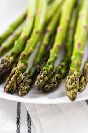 Serving steamed asparagus on a white plate with lemon wedges.の写真素材