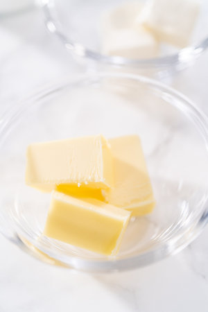 Cubed sticks of butter in a small glass mixing bowl.の写真素材
