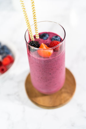 Freshly made mixed berry smoothie garnished with fresh berries and paper straws.の写真素材