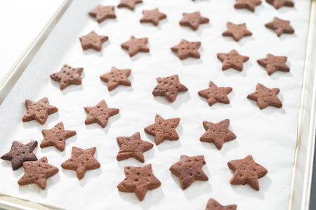 Cooling freshly star-shaped baked chocolate graham crackers on the baking sheet lined with parchment paper.の写真素材