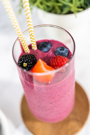 Freshly made mixed berry smoothie garnished with fresh berries and paper straws.の写真素材
