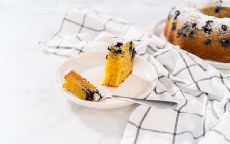Slicing freshly baked lemon blueberry bundt cake with powdered sugar dusting.