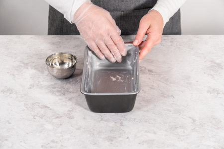 Greasing loaf pan with vegetable shortening to bake sweet pumpkin bread.
