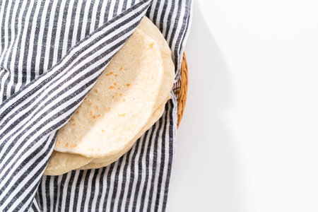 Stack of freshly baked flatbread wrapped in a kitchen towel.の写真素材