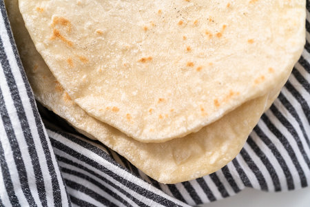Stack of freshly baked flatbread wrapped in a kitchen towel.の写真素材