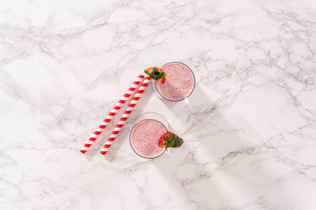 Flat lay. Freshly made healthy breakfast strawberry banana smoothie garnished with fresh strawberry and paper straw.の写真素材