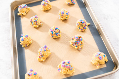 Chilled cookie dough scoops on the baking sheet to bake unicorn chocolate chip cookies.