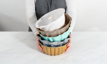 Stack of different colors and shapes bundt cake pans.