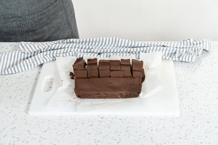 Cutting plain homemade fudge into small pieces on a white cutting board.の写真素材