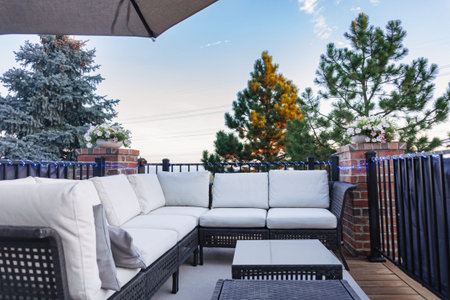 Morning on a summer day. Fully furnished backyard patio with a grill, sitting area, and umbrella.
