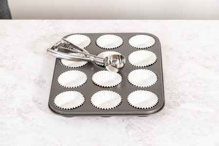 Lining cupcake baking pan with foil cupcake liners to bake unicorn rainbow chocolate cupcakes.の写真素材