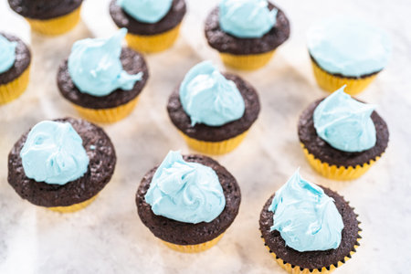 Decorating chocolate cupcakes with buttercream frosting and rainbow candy.