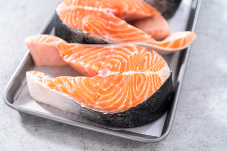Farm-raised salmon steaks on a cooking tray with a parchment paper.の写真素材