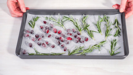 Step by step. Covering fresh cranberries and rosemary in sugar to decorate chocolate bundt cake with chocolate frosting.の写真素材
