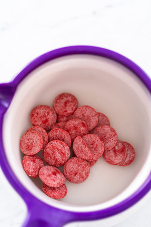 Melting red chocolate chips in a candy melting pot to make chocolate lips and heart shaped...