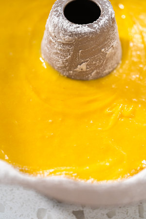 Pouring cake batter into a greased bunt cake pan to bake a simple vanilla bundt cake.の写真素材