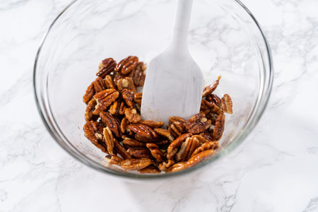 Mixing ingredients in a large glass mixing bowl to make toasted pecans.
