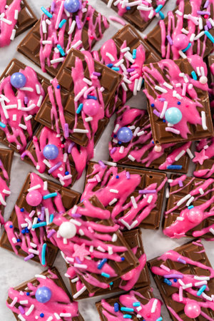 Gourmet dark mini chocolates with drizzled pink chocolate and fancy sprinkles on top.