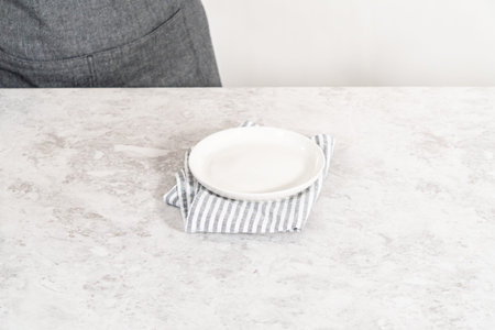 Empty a white plate on the white kitchen counter.