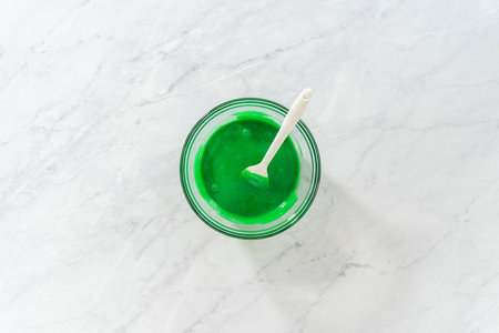 Flat lay. Mixing wet ingredients in a small glass mixing bowl to prepare green fudge with red hearts.の写真素材