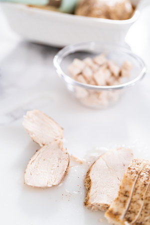Slicing freshly baked chicken breast on a white cutting board.の写真素材