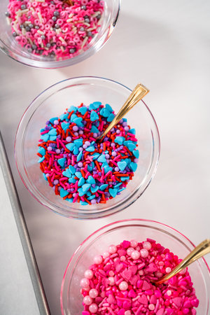 Drizzling melted chocolate over chocolate-dipped pretzels rods and decorating with sprinkles to make chocolate-covered pretzel rods for Valentines Day.の写真素材