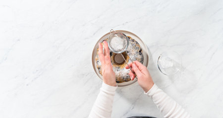 Flat lay. Dusting freshly baked lemon blueberry bundt cake with powdered sugar.の写真素材