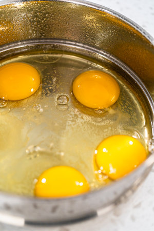 Filling metal pressure cooker insert with raw eggs to cook boiled eggs for potato salad.の写真素材