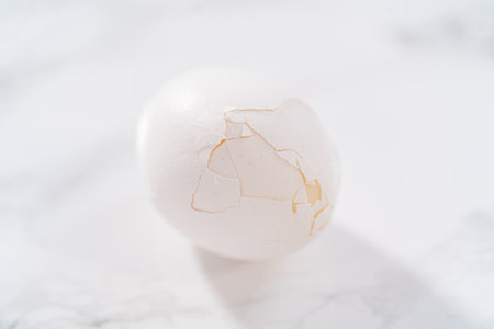 Peeling hard-boiled eggs at the marble kitchen counter.の写真素材
